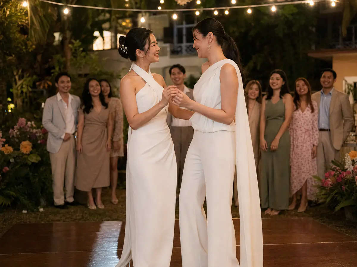 คู่บ่าวสาวหญิงชาวไทยเต้นรำและยิ้มให้กันในงานเลี้ยงอบอุ่นท่ามกลางเพื่อนสนิท