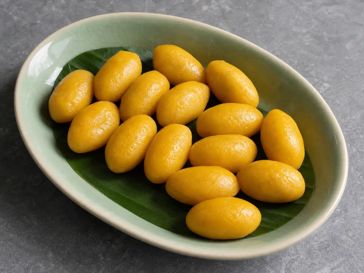เม็ดขนุนสีทองทรงรีคล้ายเมล็ดขนุนบนใบตอง