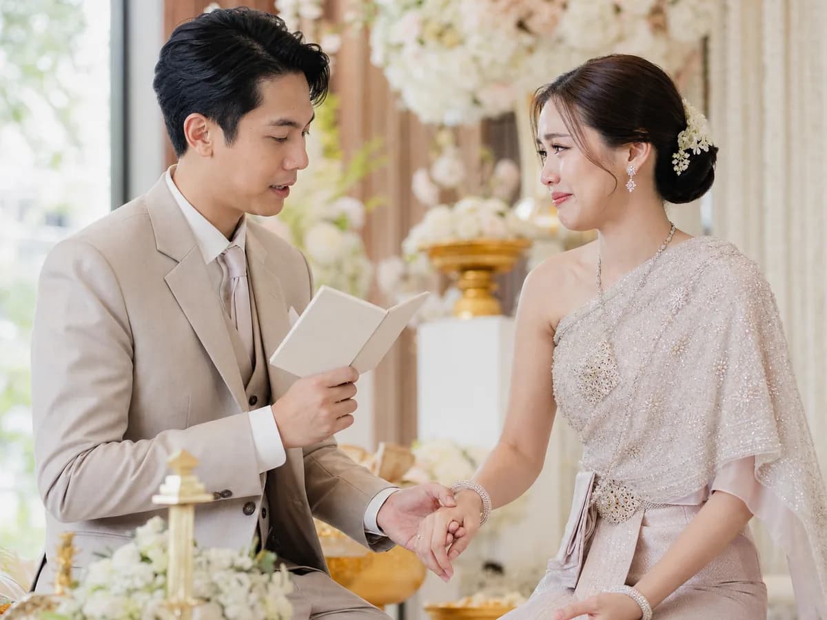 เจ้าบ่าวกล่าวคำปฏิญาณจากสมุดเล่มเล็กขณะจับมือเจ้าสาวที่กลั้นน้ำตา