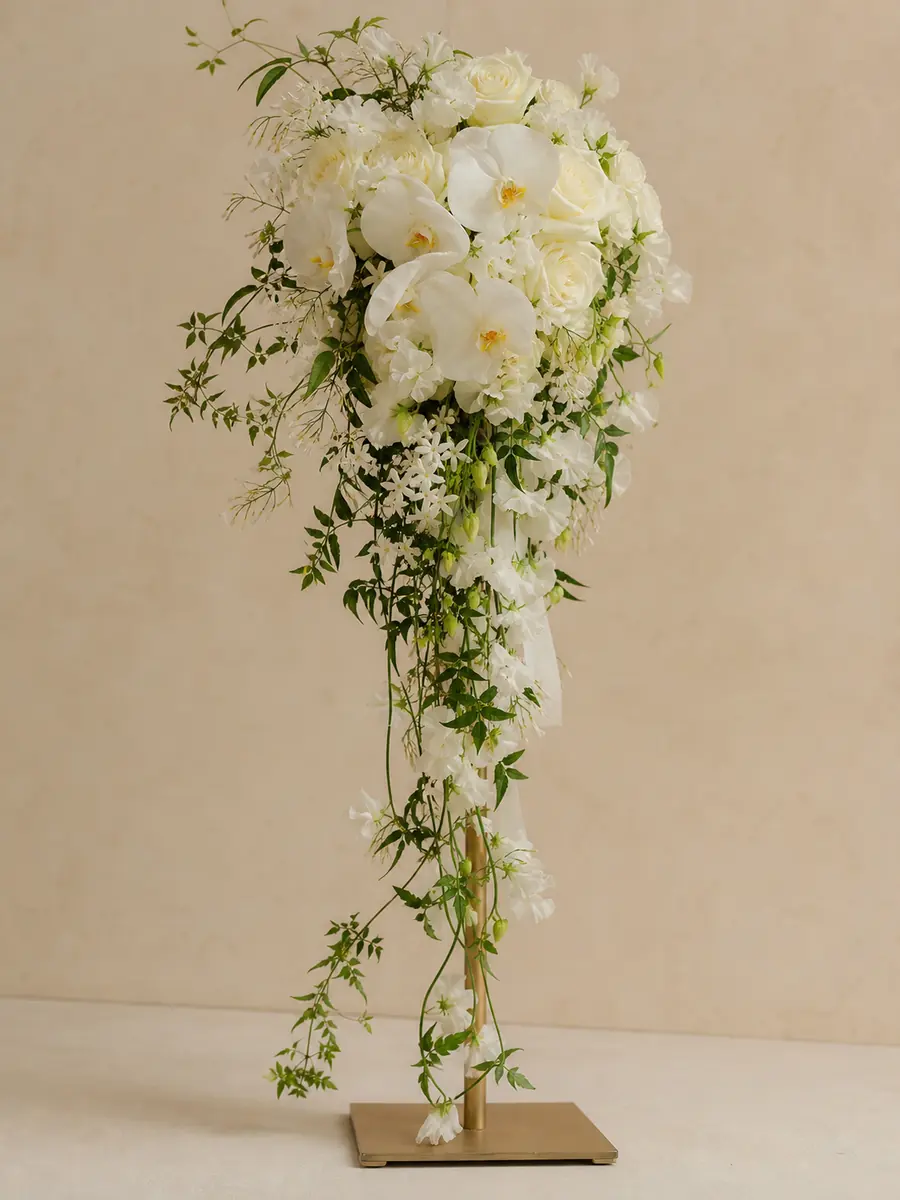 Waterfall-shaped bridal bouquet with orchids, roses and naturally trailing greenery