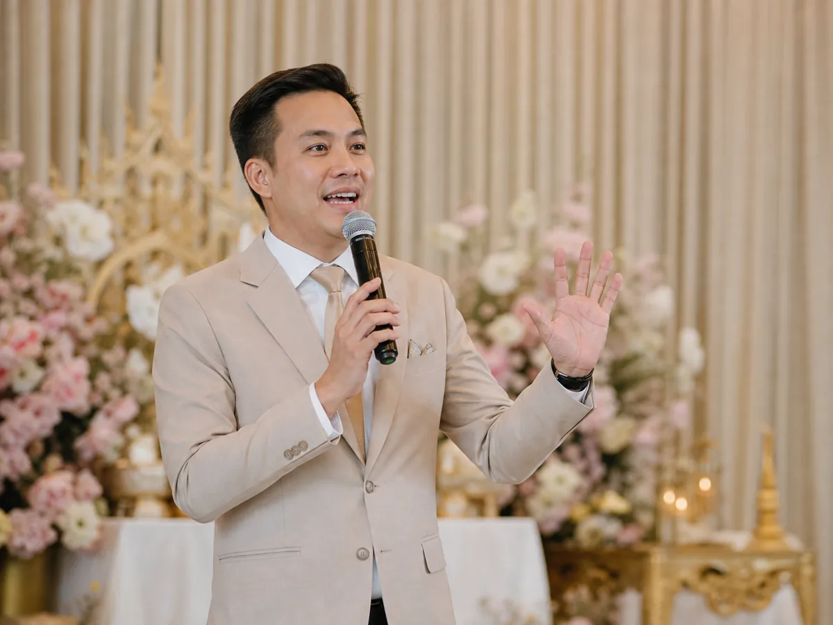 A wedding MC holding a microphone announcing the next cue in front of the reception stage