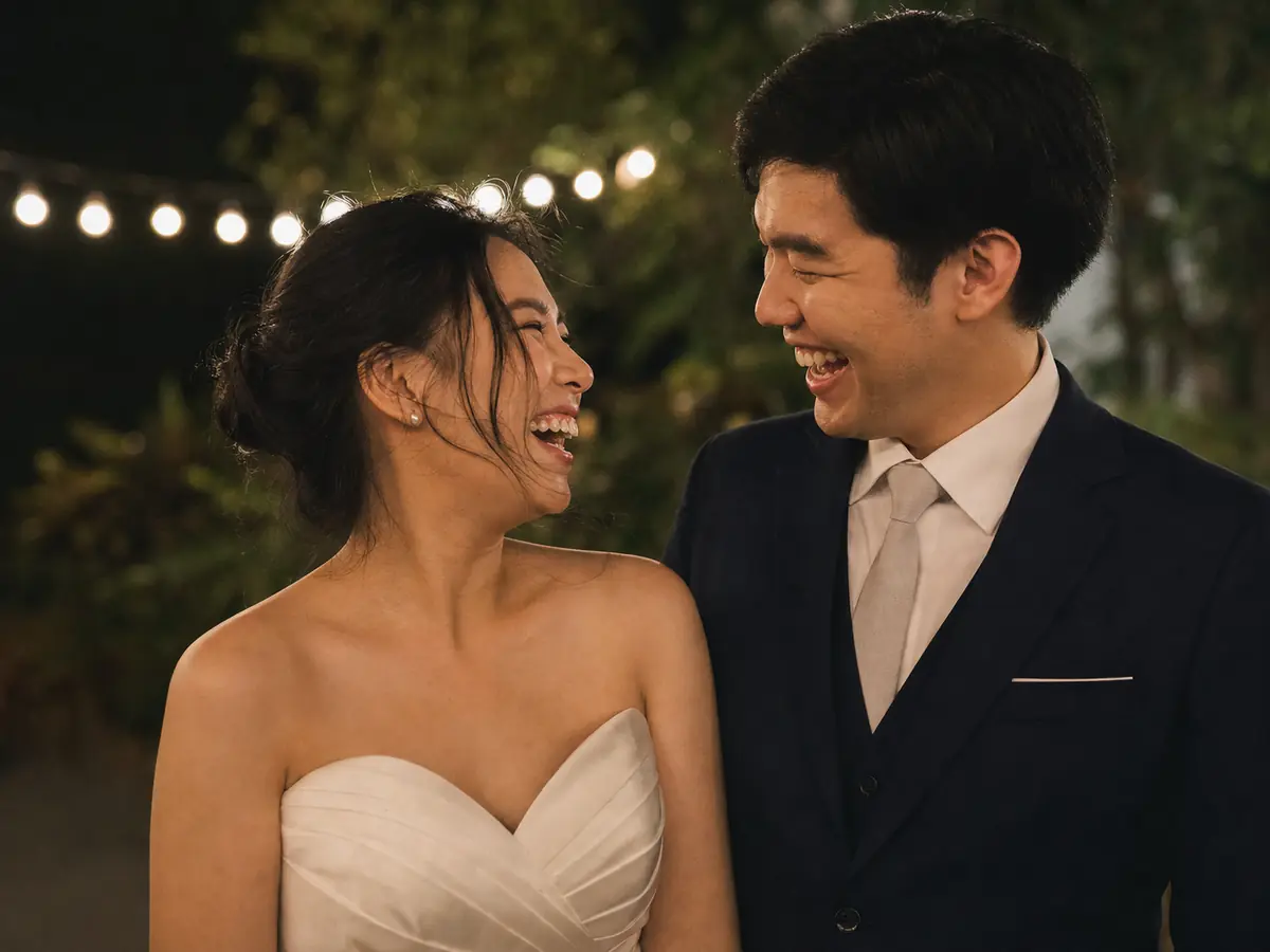 Documentary-style moment of a Thai wedding couple laughing together at an evening reception